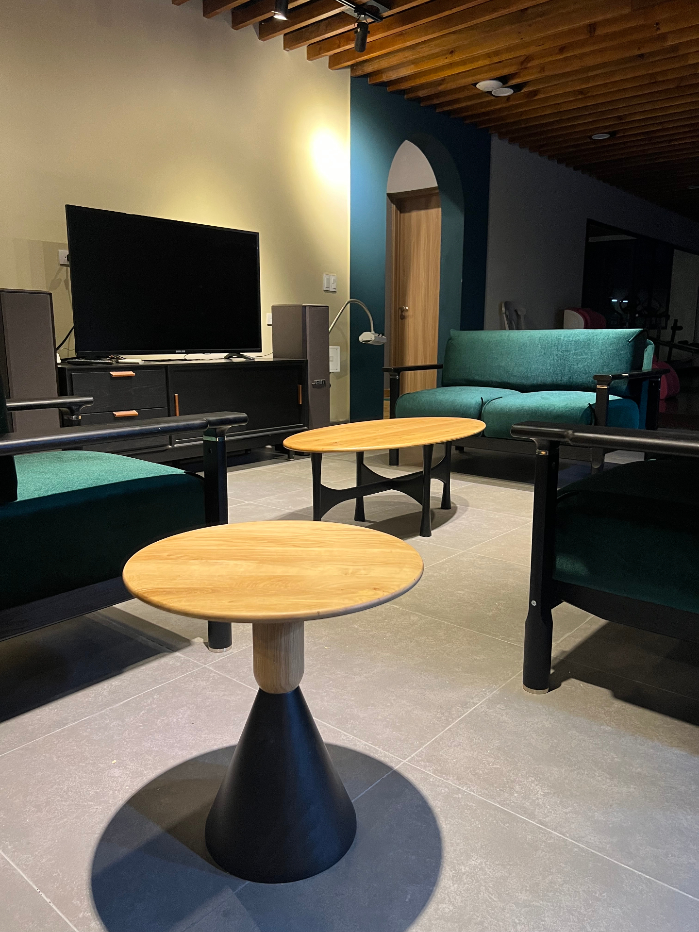 OEM showroom lifestyle — walnut round side tables with black oak media console